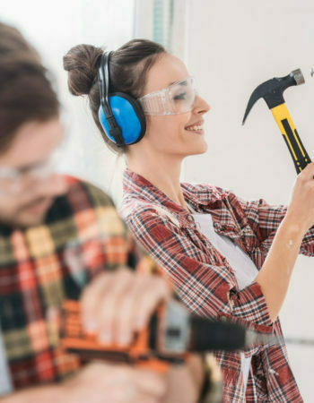 selective focus of young couple hammering and drilling wall during renovation