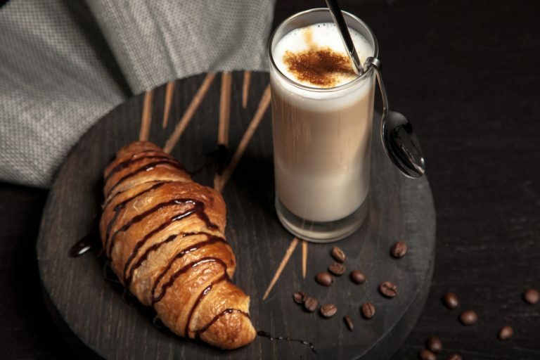 a cup of coffee and croissants on a table
