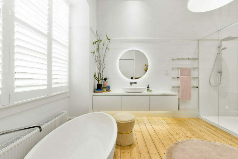 a bathroom with a mirror and a plant in the corner