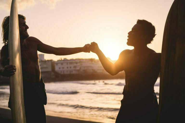 Happy multiracial surfers having fun on the beach
