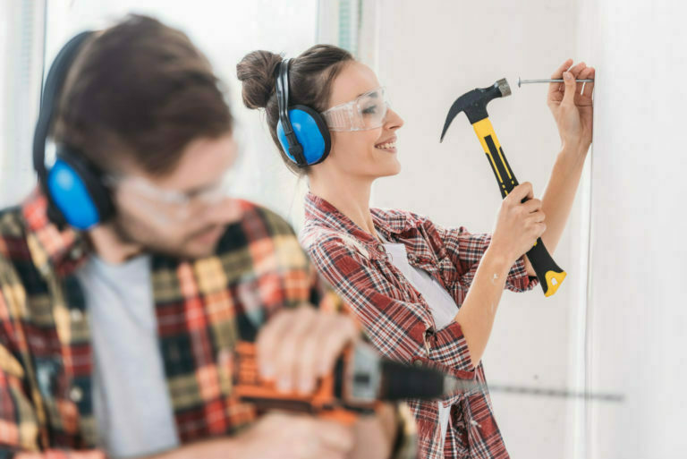 selective focus of young couple hammering and drilling wall during renovation